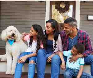 California family and their dog sit on the front porch of their home