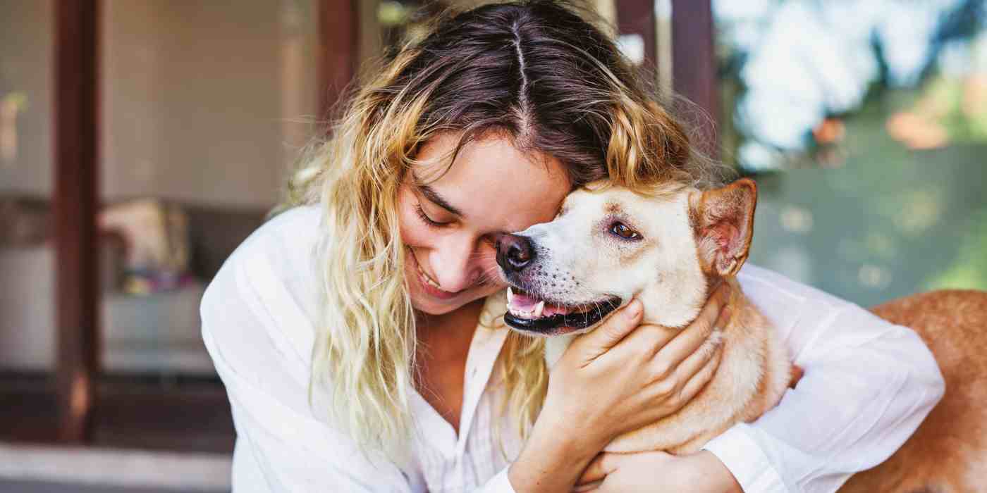Image shows a woman cuddling a yellow lab mix dog. Banner for Edmonton Pet Adoptions Guide.