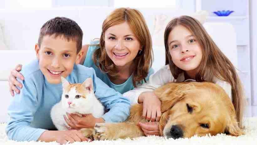 A mum with her 2 kids pose with a dog and cat