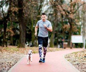 Photo Man jogs with his dog running beside him