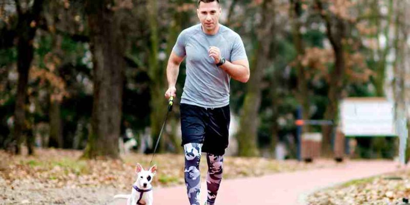Man jogs with his dog running beside him