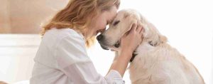 Woman cuddles a white dog