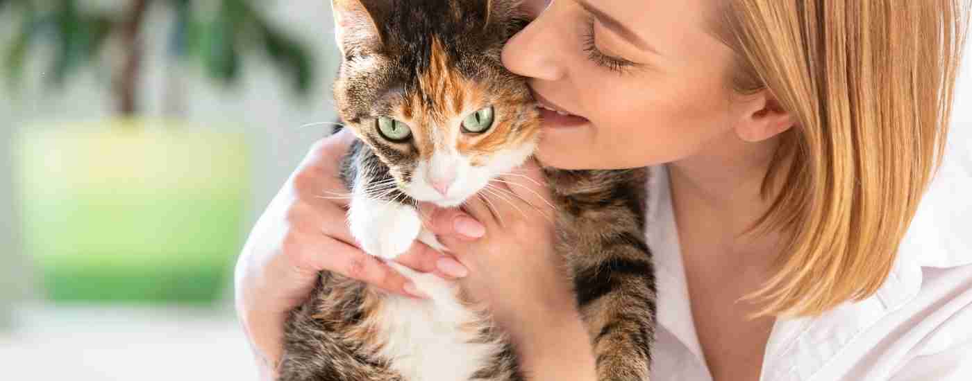 Worcester pet rehoming services banner shows a woman cuddling a pretty calico tabby tuxedo cat