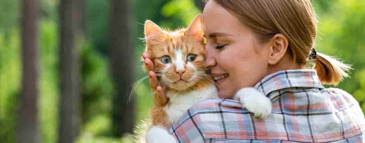 Boston pet rehoming services banner - woman cuddles orange tabby cat outdoors