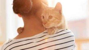 WOMAN CARRYING A CAT ON HER SHOULDER