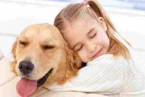 Young girl snuggles her golden retriever dog