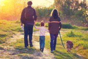 Small family faced with rehoming a dog pictured from behind walking their dog